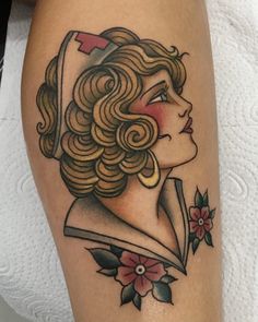 a woman's leg with a tattoo on it that has flowers and a cross in her hair