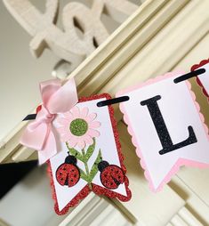 ladybug banner hanging on the mantle with pink ribbon and bow, decorated with flowers