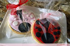 two decorated cookies in the shape of ladybugs on a tray with red ribbon