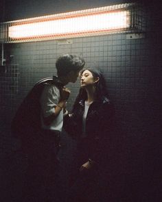 a man and woman standing next to each other in front of a wall with lights