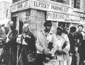 an old black and white photo of people standing in front of a building with signs on it