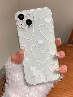 a woman holding up her phone case with hearts on the front and back cover in white