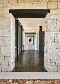 an open door leading to a hallway with stone walls and tile flooring on both sides