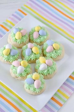 small cookies decorated with green icing and colorful candies on a square white plate