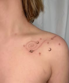 a woman's chest with small stars and planets on the left side of her shoulder