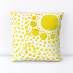 a yellow and white pillow with dots on it's side, against a white wall