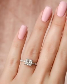 a woman's hand with a pink manicured nail polish and an engagement ring