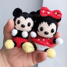 two small crocheted mickey and minnie mouse dolls are held in the palm of someone's hand