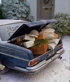 an old car is loaded with boxes and presents in the snow, while it's parked outside