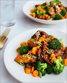 two white plates topped with meat and broccoli on top of a table next to silverware