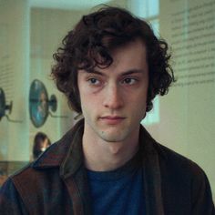 a young man with curly hair looks at the camera