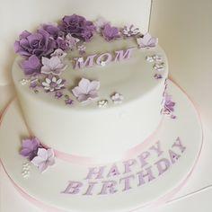 a white cake with purple flowers and the words mom on it