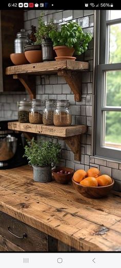 a wooden counter top sitting under a window next to a bowl of oranges and potted plants