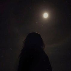 a person standing in the dark looking at the moon