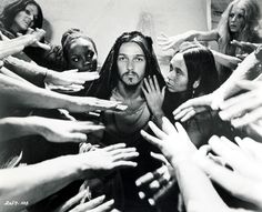 a group of people reaching out their hands to touch jesus