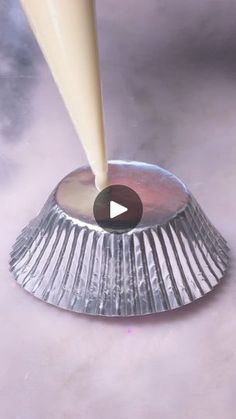 a person is pouring milk on top of a silver cupcake