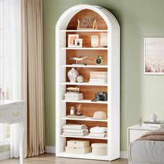 a white bookcase in a bedroom with green walls