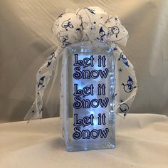 a clear glass block with the words let it snow on it and some lights inside