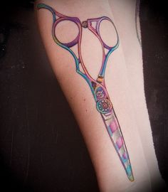 a colorful tattoo on the arm of a woman with scissors in it's blades