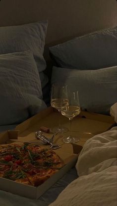 a pizza sitting on top of a bed next to a glass of wine