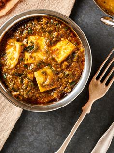 a bowl filled with tofu and spinach next to silverware