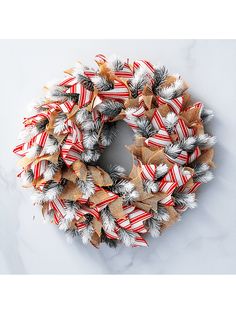 a christmas wreath with red, white and silver decorations on it sitting on a marble surface