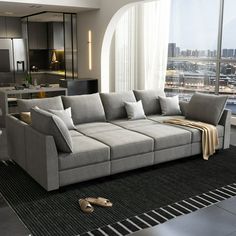 a living room filled with furniture and a large window overlooking a cityscape in the distance