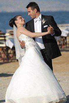 a bride and groom dancing on the beach