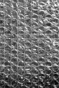 a close up view of some plastic bottle caps on a glass door screen, with the background textured in black and white