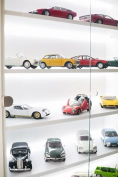 a display case filled with lots of different types of toy cars on shelves next to each other