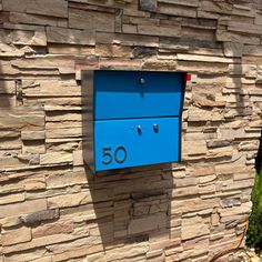 a blue mailbox mounted to the side of a stone wall