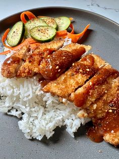 a plate with rice, cucumbers and chicken next to some sauce on it