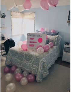 a bed topped with lots of pink and white balloons next to a sign that says happy birthday