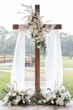 a cross decorated with white flowers and greenery