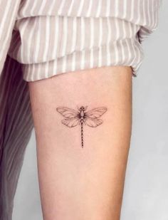 a small dragonfly tattoo on the right thigh, with an arrow in it's center