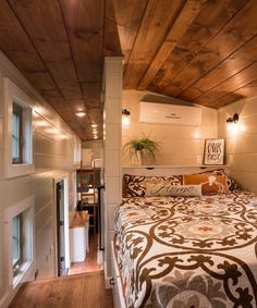 a bed in a room with wooden ceiling and white walls, along with wood flooring