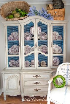 an old china cabinet with plates and baskets on top