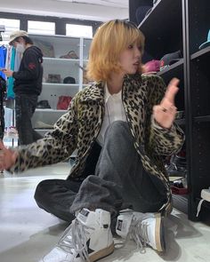 a woman sitting on the floor in front of a shelf with shoes and other items