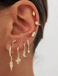 a close up of a person wearing gold ear piercings with diamond stars and leaves on them