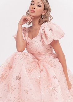 a woman in a pink dress posing for the camera with her hand on her chin