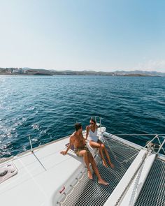 two people sitting on the bow of a boat