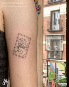 a small tattoo on the arm of a woman's left arm, with an image of a fan in it