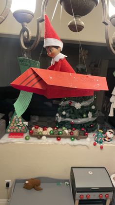 an elf is sitting on top of a christmas tree in the shape of a rocket