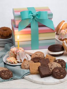 a table topped with lots of different types of cakes and cookies next to a lit candle