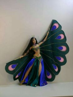 a woman dressed in a costume and holding a peacock wings on top of a shelf