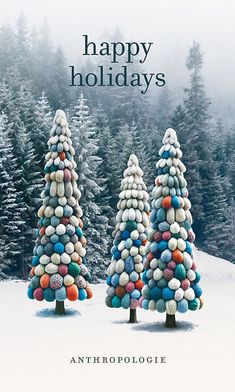 two christmas trees made out of balls in the snow with words happy holidays above them