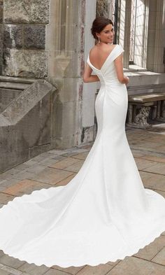 a woman in a white wedding dress standing on a brick floor with her back to the camera