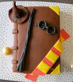 a birthday cake decorated to look like a harry potter book with glasses and wands on top