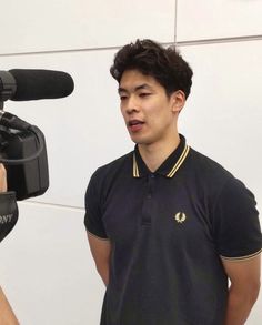 a young man standing in front of a microphone and recording something on a tripod