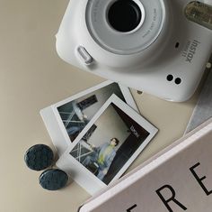 a white camera sitting on top of a table next to two pictures and a button